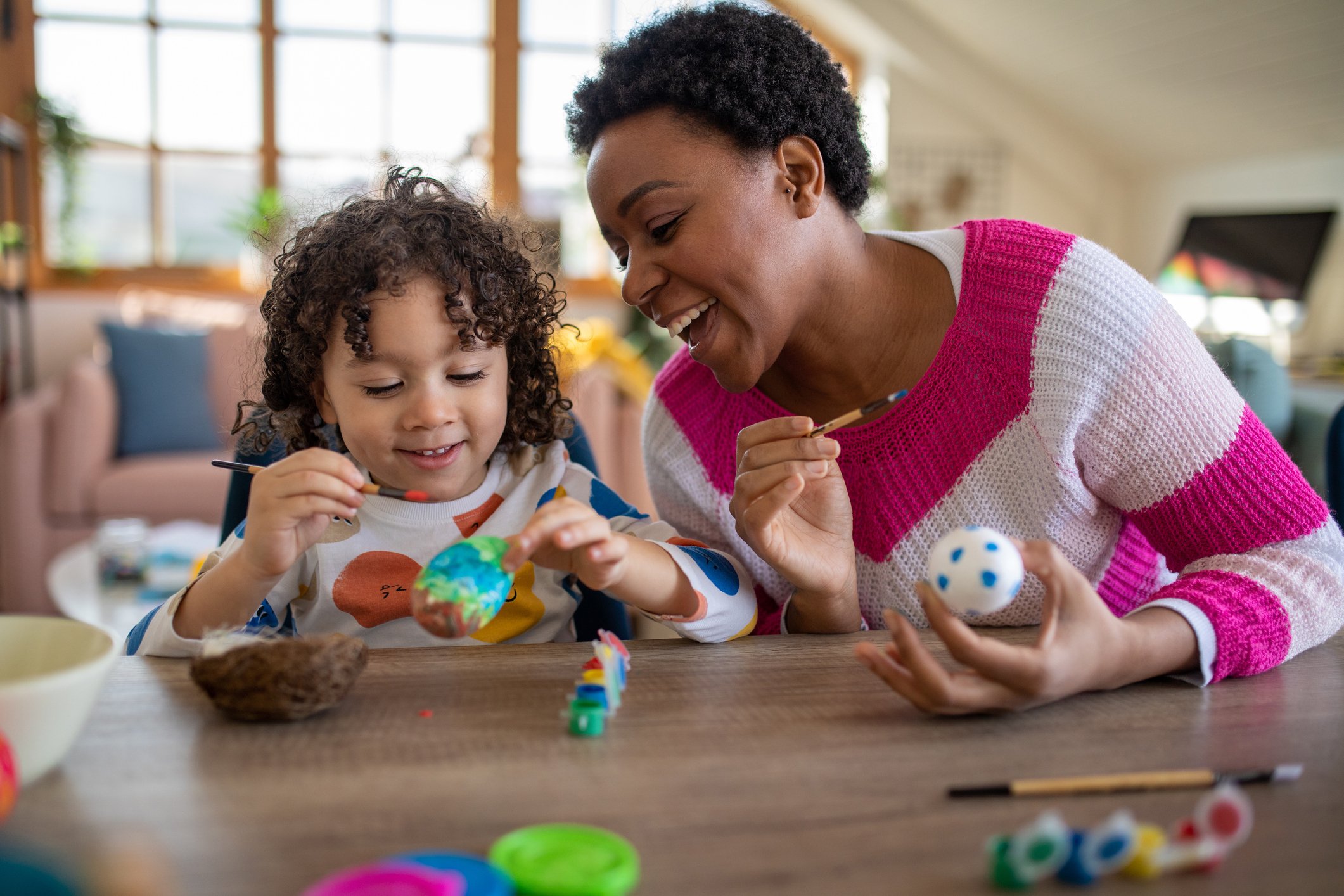 African mother and her multiracial son coloring Easter eggs at home