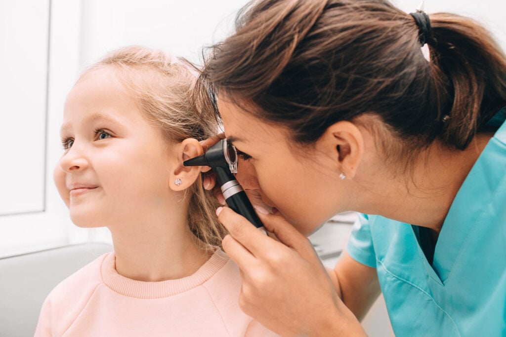 Pediatrician examining little patient with otoscope, hearing exam of child